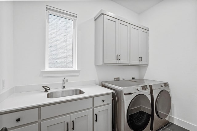 laundry room featuring cabinets, dark tile patterned flooring, sink, and washing machine and clothes dryer