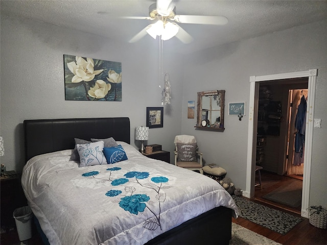 bedroom with a textured ceiling, wood-type flooring, and ceiling fan