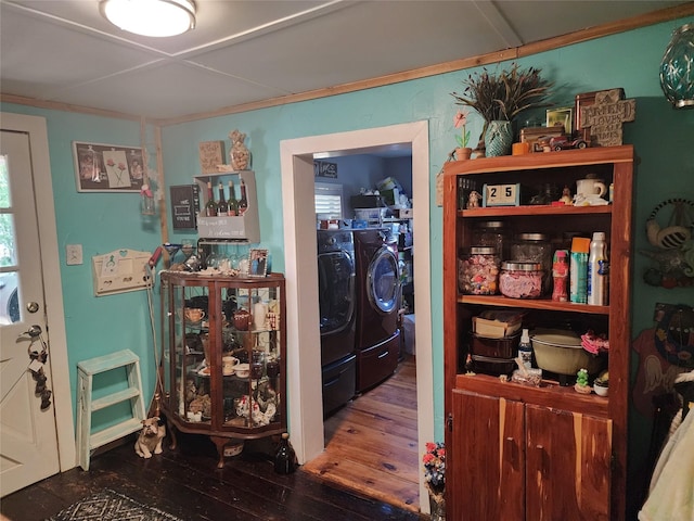 clothes washing area featuring crown molding, washing machine and clothes dryer, and dark hardwood / wood-style flooring