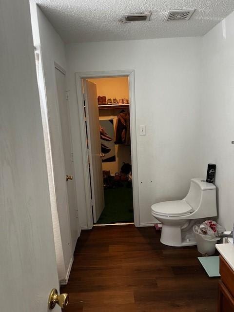 bathroom featuring vanity, toilet, wood-type flooring, and a textured ceiling