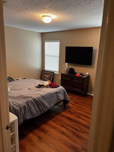 bedroom featuring dark hardwood / wood-style flooring and a textured ceiling