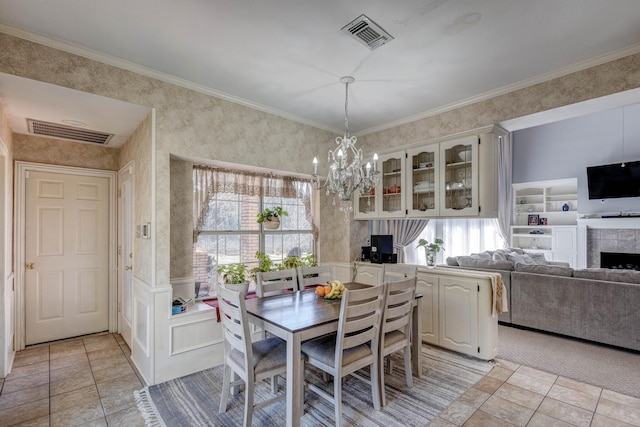 dining room with a tiled fireplace, plenty of natural light, ornamental molding, and a chandelier