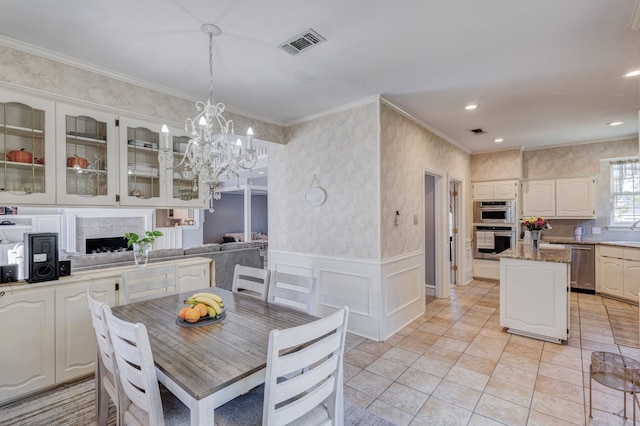 kitchen featuring crown molding, a center island, hanging light fixtures, stainless steel appliances, and white cabinets