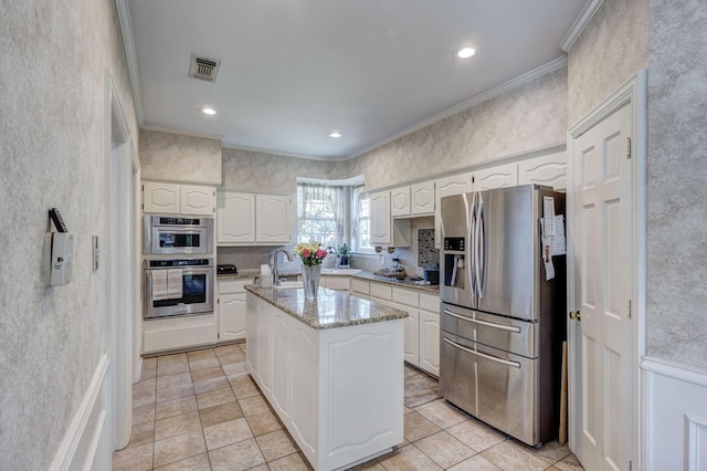 kitchen featuring white cabinetry, appliances with stainless steel finishes, a center island, and ornamental molding