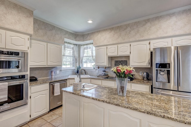 kitchen with light stone counters, stainless steel appliances, crown molding, and white cabinets