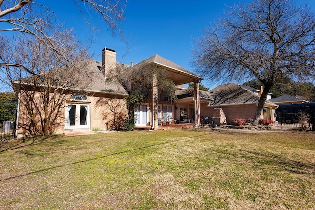 back of property featuring a lawn and french doors