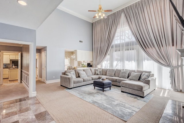 living room featuring ceiling fan, ornamental molding, light carpet, and a high ceiling