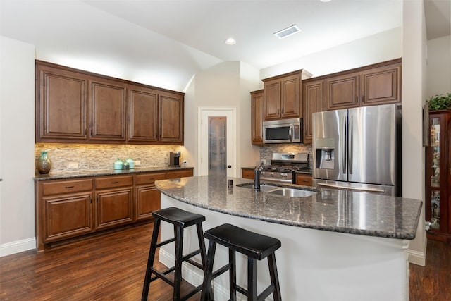 kitchen with stainless steel appliances, a breakfast bar area, dark hardwood / wood-style floors, and a center island with sink