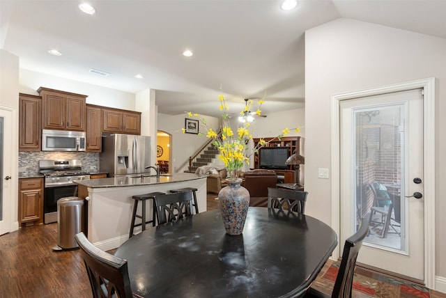 dining area with sink, dark wood-type flooring, and vaulted ceiling