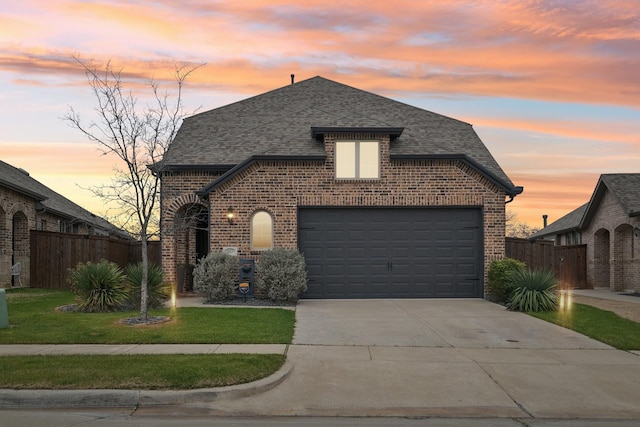 french country style house featuring a garage and a lawn