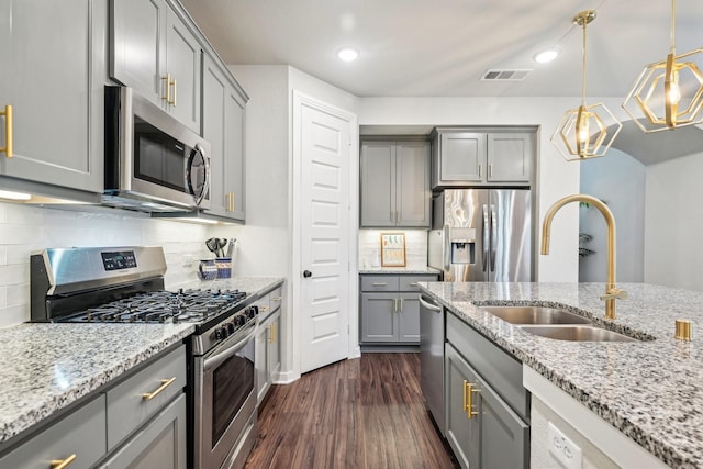 kitchen featuring sink, gray cabinetry, hanging light fixtures, stainless steel appliances, and light stone counters