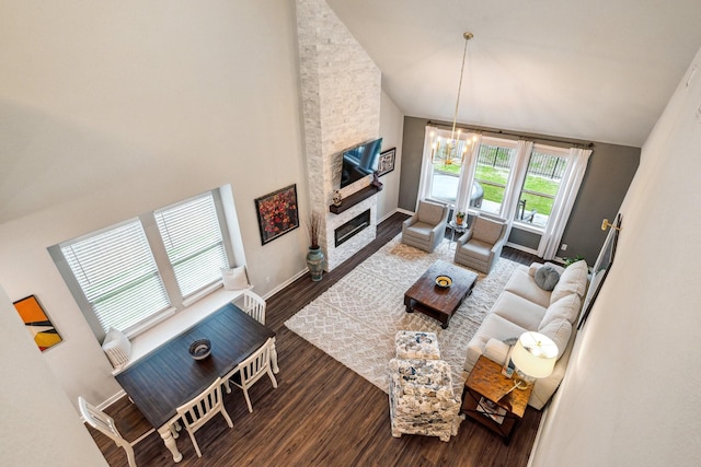 living room featuring hardwood / wood-style flooring, high vaulted ceiling, a fireplace, and an inviting chandelier