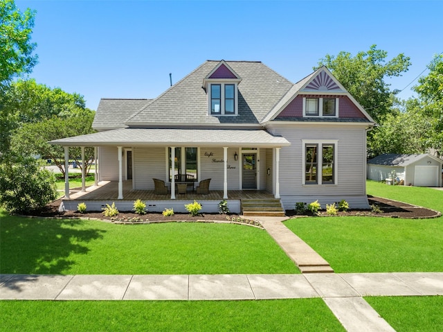 farmhouse inspired home featuring a porch, a garage, an outdoor structure, and a front lawn