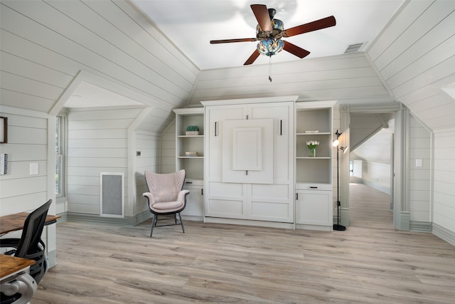 interior space featuring vaulted ceiling, wood walls, ceiling fan, and light hardwood / wood-style flooring