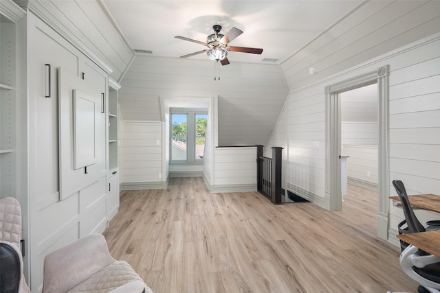 office area with ceiling fan, wood walls, and light wood-type flooring