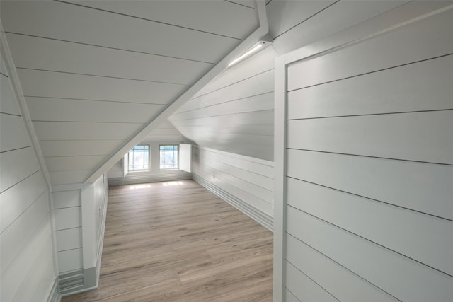 hallway with lofted ceiling, wood ceiling, wood walls, and light wood-type flooring