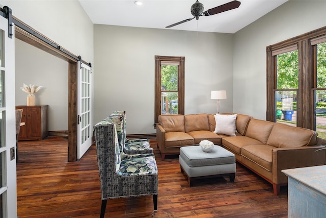 living room with a wealth of natural light, dark wood-type flooring, and a barn door