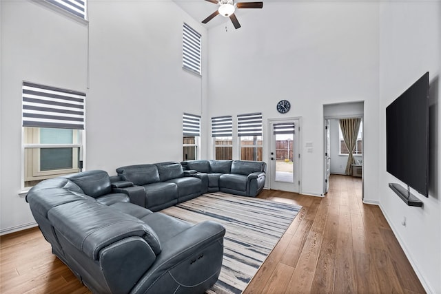 living room with ceiling fan, hardwood / wood-style floors, and a high ceiling