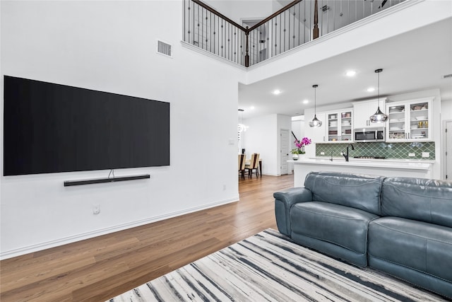 living room with sink, light hardwood / wood-style flooring, and a high ceiling