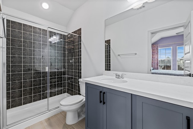 bathroom with vanity, toilet, a shower with shower door, and vaulted ceiling