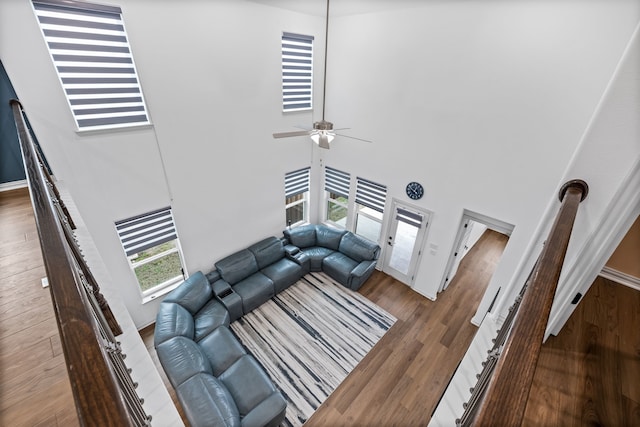 living room featuring a towering ceiling, dark wood-type flooring, and ceiling fan