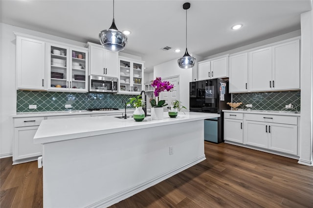 kitchen with appliances with stainless steel finishes, decorative light fixtures, a center island with sink, and white cabinets