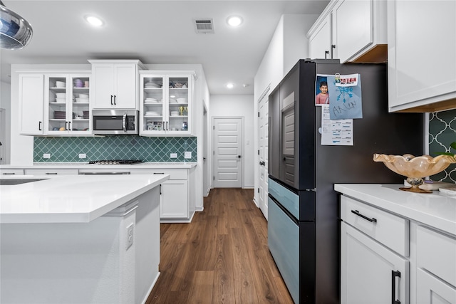 kitchen featuring tasteful backsplash, white cabinetry, appliances with stainless steel finishes, and dark wood-type flooring