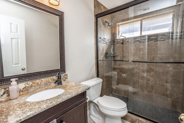 bathroom with vanity, toilet, and a shower with shower door