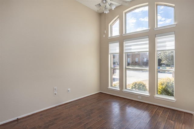 unfurnished room with dark wood-type flooring, a towering ceiling, and a wealth of natural light