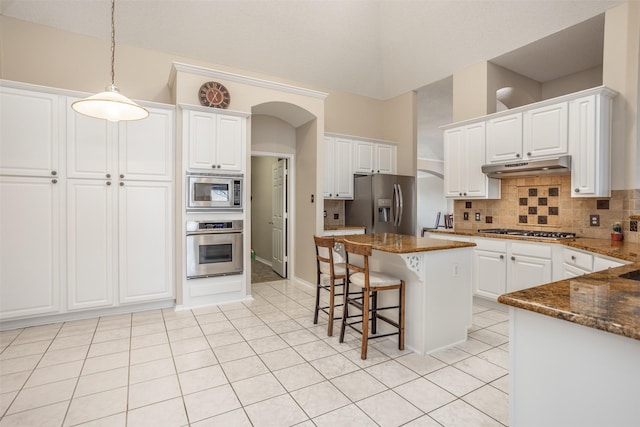 kitchen featuring tasteful backsplash, white cabinetry, dark stone counters, a center island, and stainless steel appliances