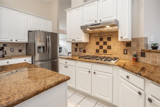 kitchen featuring tasteful backsplash, white cabinetry, dark stone counters, light tile patterned floors, and stainless steel appliances