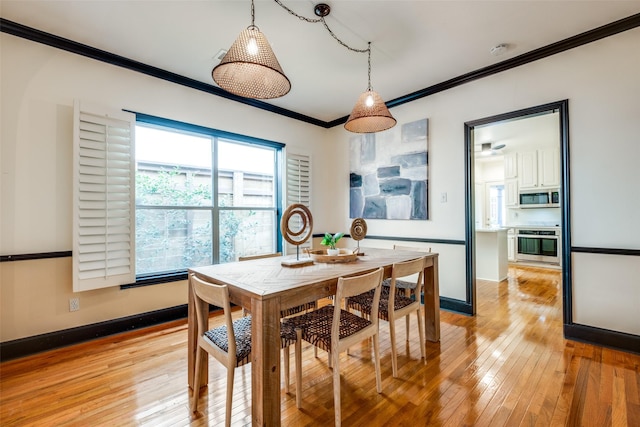 dining area featuring ornamental molding and light hardwood / wood-style floors