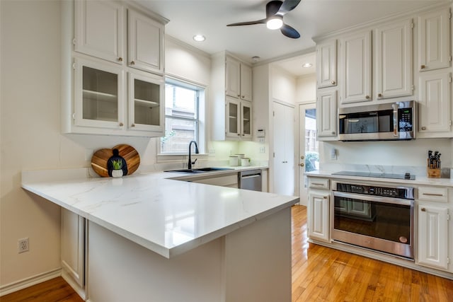 kitchen featuring sink, white cabinetry, light hardwood / wood-style flooring, kitchen peninsula, and stainless steel appliances