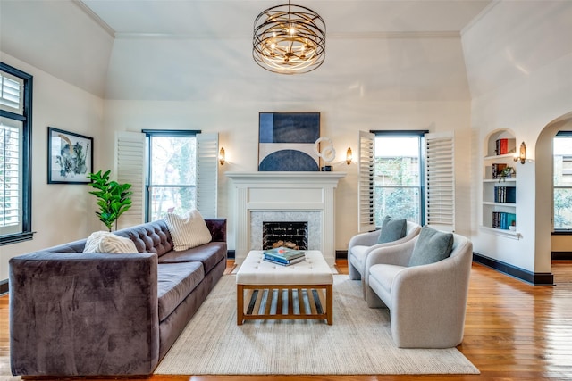 living room featuring crown molding, light hardwood / wood-style flooring, a high end fireplace, and a wealth of natural light