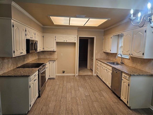 kitchen featuring sink, white cabinetry, crown molding, dark stone countertops, and appliances with stainless steel finishes