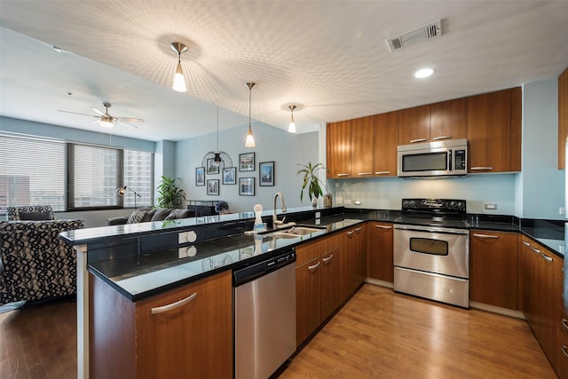 kitchen featuring sink, wood-type flooring, hanging light fixtures, appliances with stainless steel finishes, and kitchen peninsula