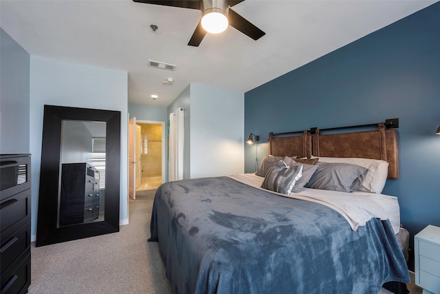 carpeted bedroom with ensuite bath and ceiling fan