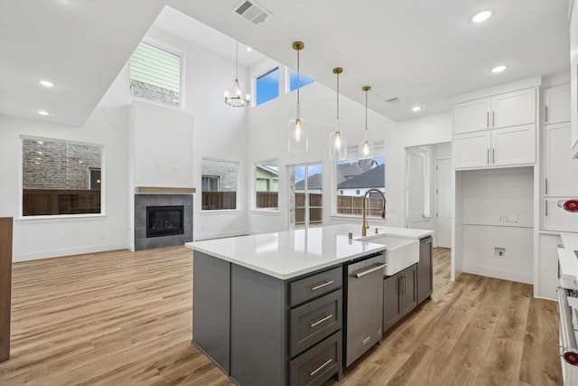 3703 Pilgrims Mews, Rowlett, TX 75088 - kitchen featuring white cabinets, dishwasher, light countertops, light wood finished floors, and a fireplace