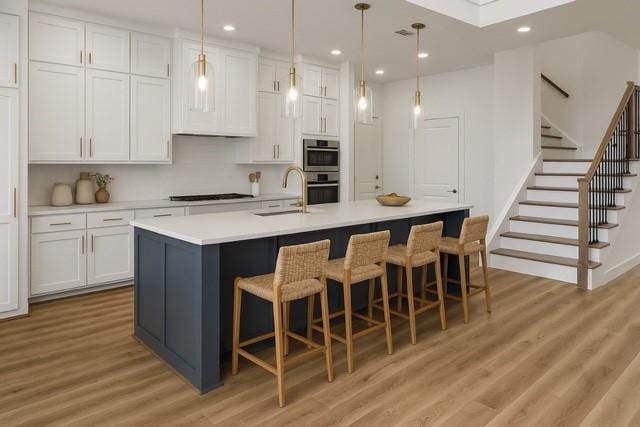 3703 Pilgrims Mews, Rowlett, TX 75088 - kitchen with light wood-type flooring, stainless steel double oven, white cabinetry, black cooktop, and recessed lighting