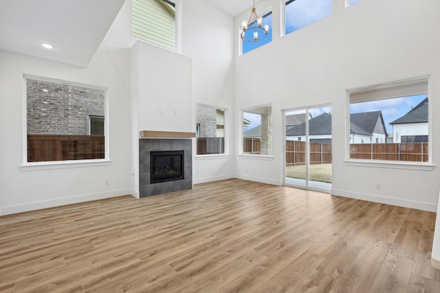 3703 Pilgrims Mews, Rowlett, TX 75088 - unfurnished living room with a tiled fireplace, wood finished floors, a high ceiling, and a chandelier