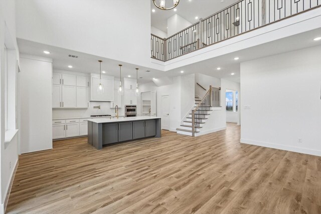 3703 Pilgrims Mews, Rowlett, TX 75088 - kitchen with white cabinets, a high ceiling, light countertops, light wood finished floors, and open floor plan