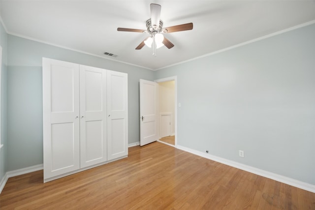 unfurnished bedroom with ceiling fan, ornamental molding, a closet, and light wood-type flooring