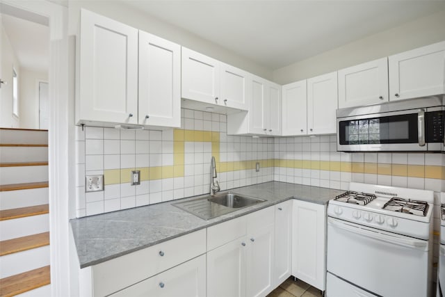 kitchen featuring tasteful backsplash, sink, gas range gas stove, and white cabinets