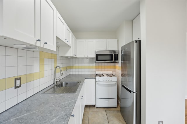 kitchen with tasteful backsplash, white cabinetry, sink, light stone counters, and stainless steel appliances