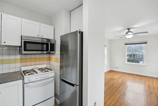 kitchen featuring white cabinetry, dark stone countertops, stainless steel appliances, tasteful backsplash, and light wood-type flooring