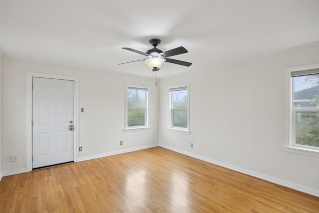 empty room featuring plenty of natural light, ceiling fan, and light wood-type flooring