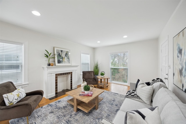 living room with a tiled fireplace and light wood-type flooring