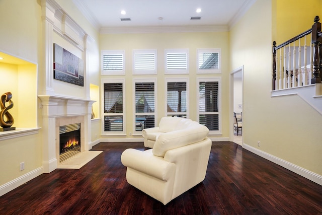 living room featuring a healthy amount of sunlight, ornamental molding, dark hardwood / wood-style flooring, and a towering ceiling