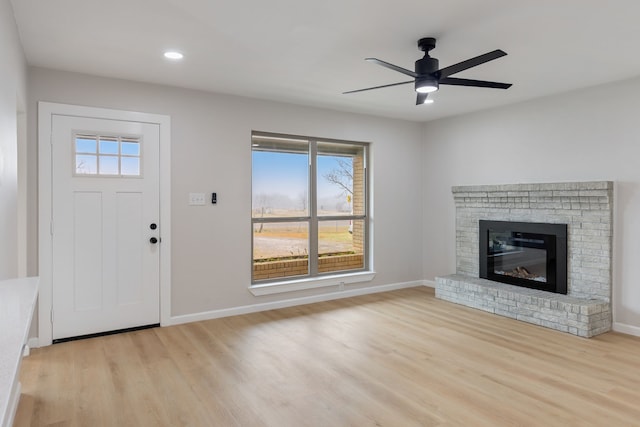 foyer with ceiling fan, a fireplace, and light hardwood / wood-style flooring