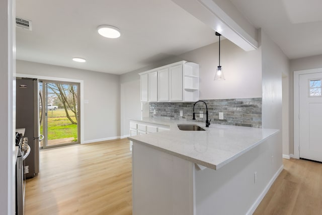 kitchen with pendant lighting, sink, white cabinets, kitchen peninsula, and light stone countertops